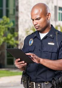 an officer uses a tablet in a parking lot