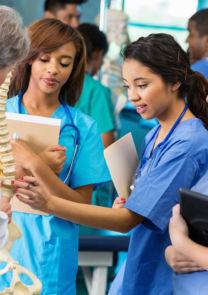 a group of nursing students discuss a skeletal model